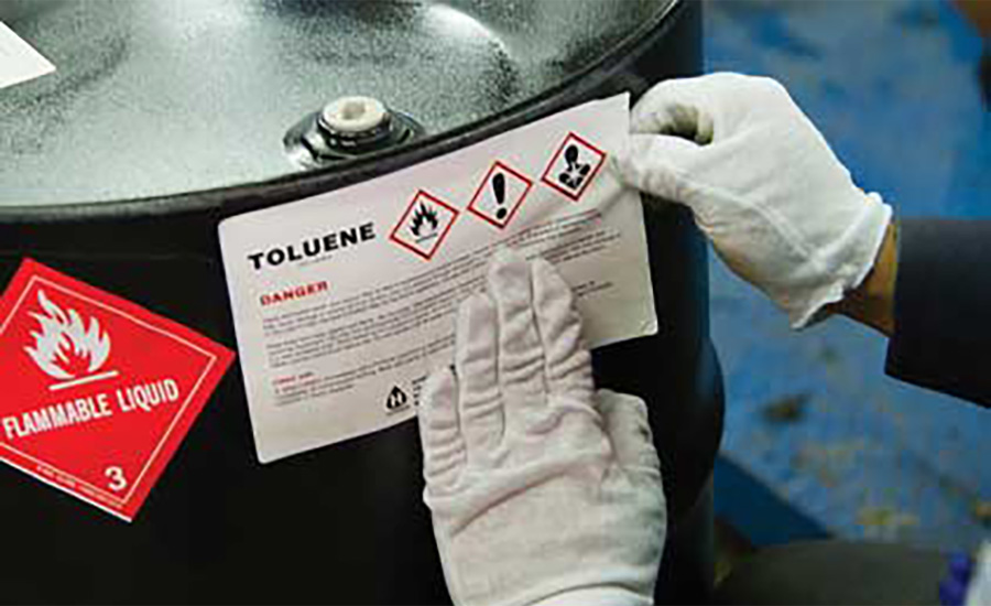 A hazardous materials label being placed onto a drum (pictured).