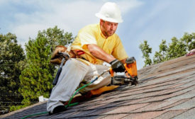 A roofer securing shingles on a roof.