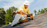 A roofer securing shingles on a roof.