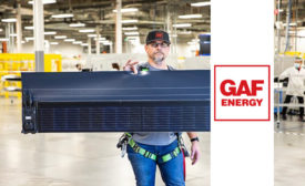 A man holding an element of GAF Energy’s Timberline Solar shingle system (pictured).