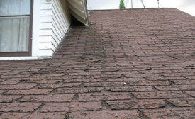 A picture of a roof with badly worn shingles.