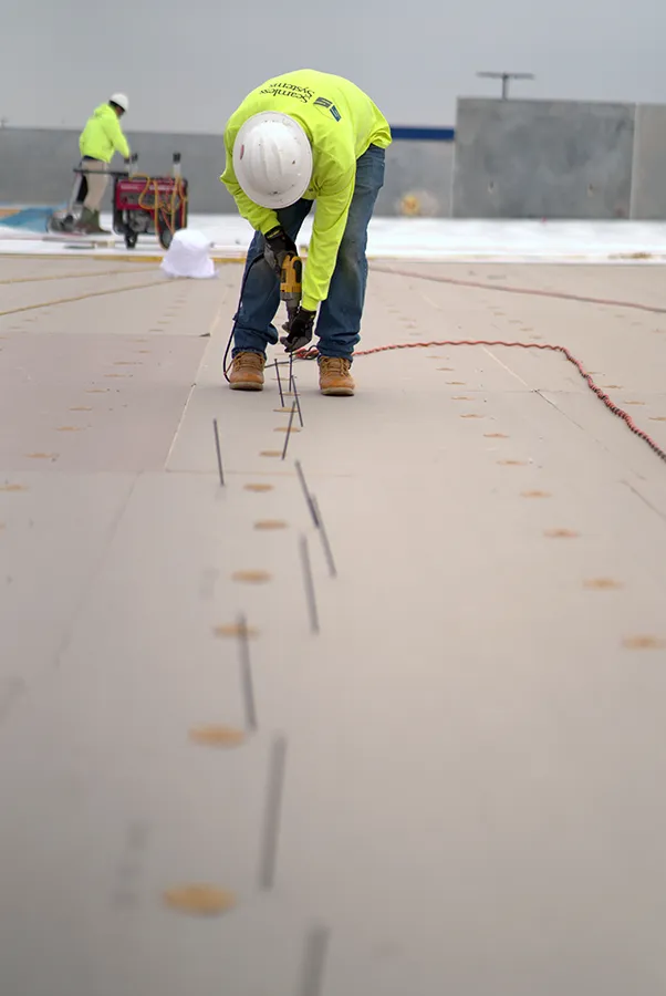 A worker securing a roofing membrane