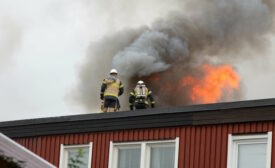 2 firefighters on top of a burning building 